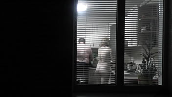 Peeping. Voyeur. Neighbor weirdo Voyeur in evening on street looks out window as bare super-sexy neighbor in kitchen preps dinner for her husband. bare in public. bare at home. Family.  Outdoor